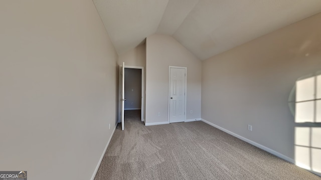unfurnished bedroom featuring vaulted ceiling, carpet flooring, and baseboards
