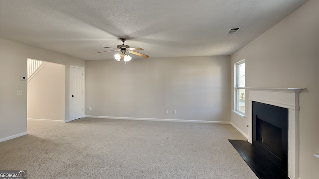 unfurnished living room featuring visible vents, carpet floors, a textured ceiling, and baseboards