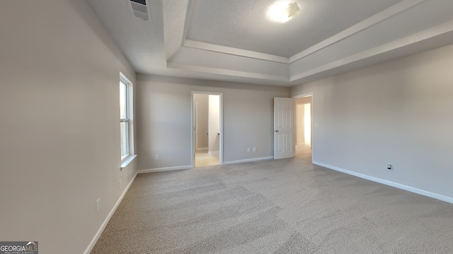 unfurnished bedroom with visible vents, baseboards, carpet floors, a textured ceiling, and a raised ceiling