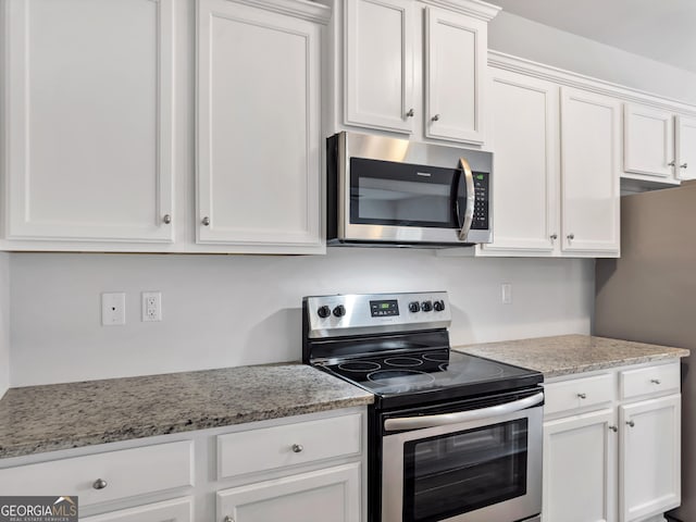 kitchen with stainless steel appliances, light stone countertops, and white cabinets