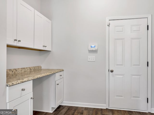 laundry room with dark wood-type flooring and baseboards