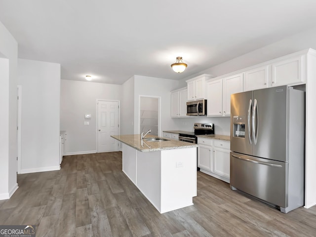 kitchen with a kitchen island with sink, a sink, wood finished floors, white cabinetry, and stainless steel appliances