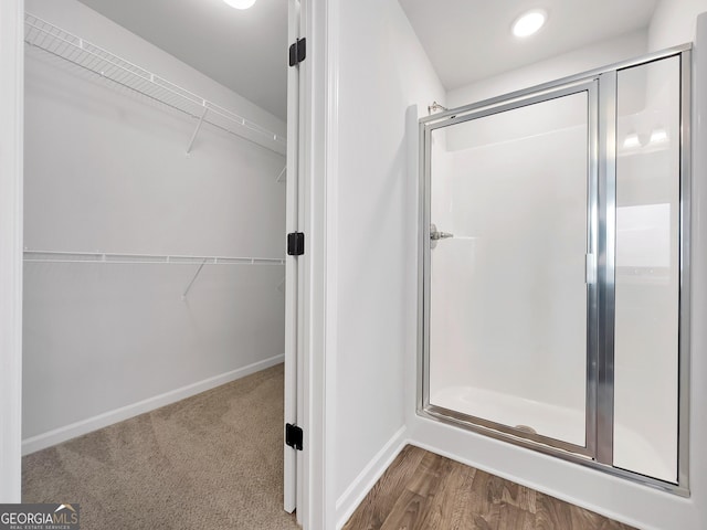 full bath featuring a walk in closet, baseboards, and a stall shower