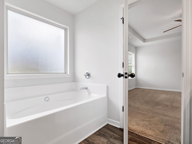 bathroom with baseboards, a garden tub, wood finished floors, and a ceiling fan