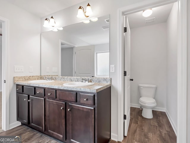 full bath featuring double vanity, toilet, wood finished floors, and a sink