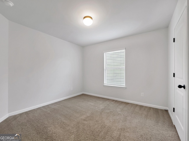 carpeted empty room featuring baseboards