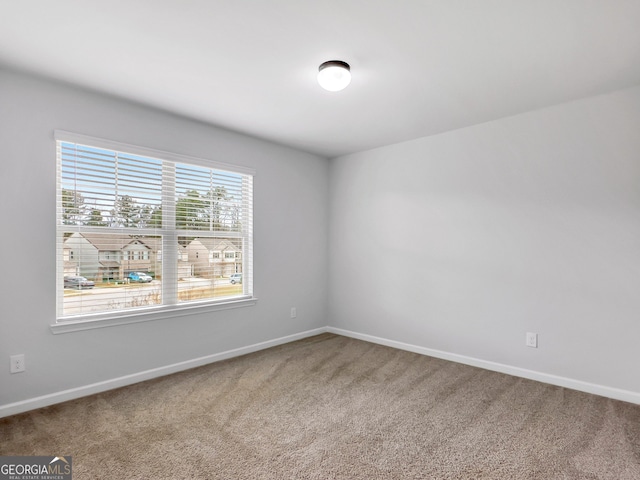 unfurnished room with carpet and baseboards