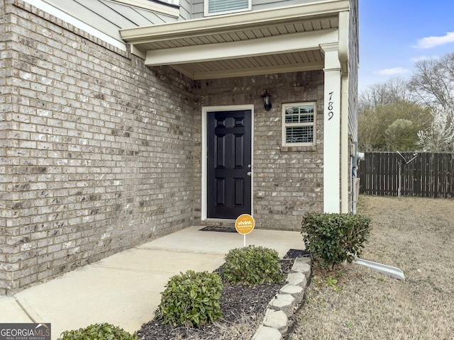 property entrance with fence and brick siding