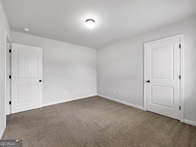 carpeted empty room featuring baseboards