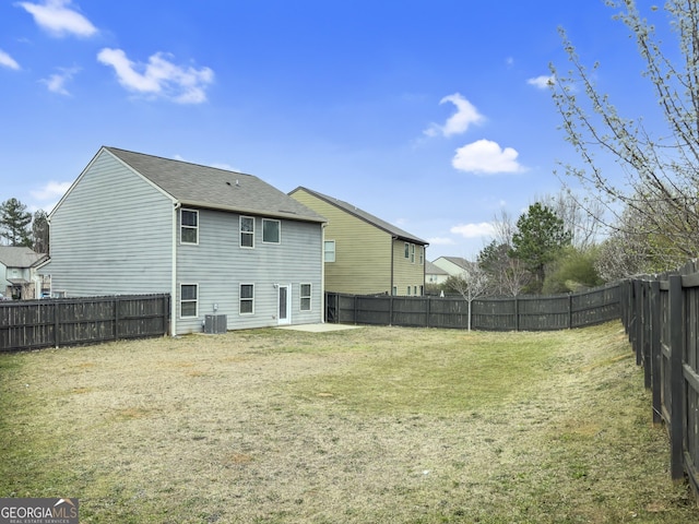 back of house featuring a fenced backyard, central AC unit, and a yard