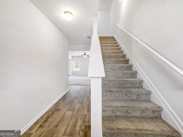 stairs featuring a ceiling fan, wood finished floors, visible vents, and baseboards