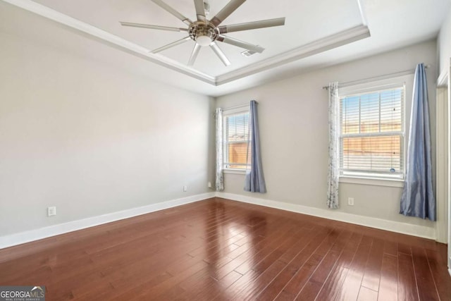 spare room featuring a tray ceiling, a ceiling fan, and dark wood-style flooring