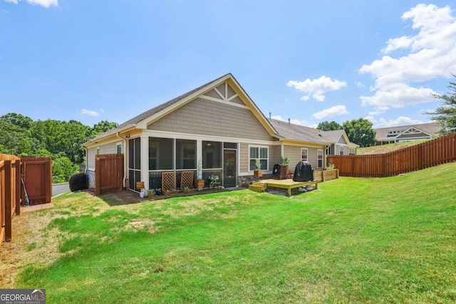 rear view of house with stone siding, a lawn, fence, and a sunroom