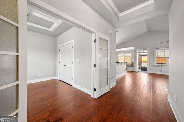 interior space with ornamental molding, baseboards, a tray ceiling, and wood-type flooring