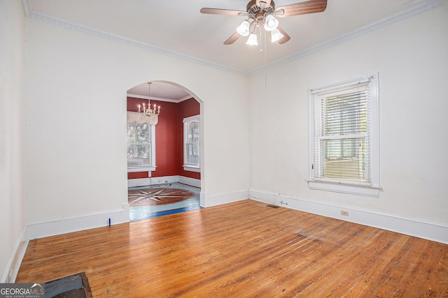 empty room featuring arched walkways, a healthy amount of sunlight, and hardwood / wood-style floors