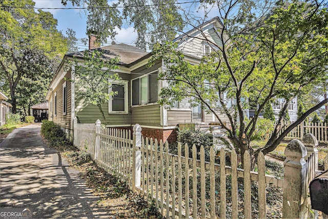 view of side of home with a chimney and fence