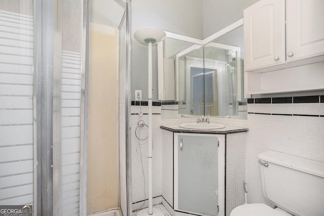 full bathroom featuring vanity, a shower stall, toilet, and tile walls