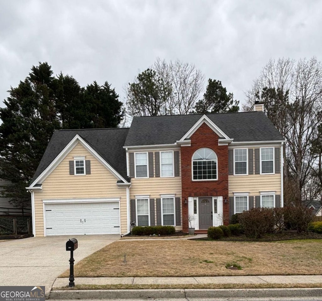 view of front facade with a chimney, an attached garage, concrete driveway, and a front yard