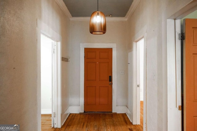 entryway with wood finished floors and crown molding