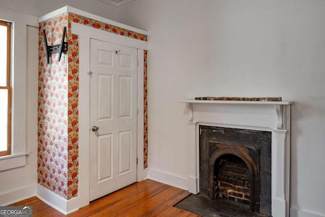 interior space featuring a fireplace with flush hearth, wood finished floors, and baseboards