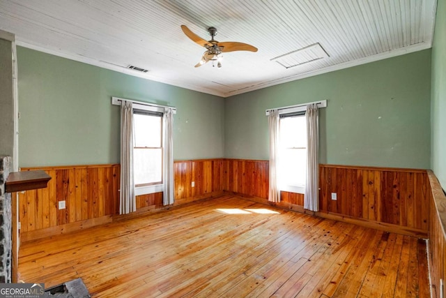 unfurnished room with a wainscoted wall, plenty of natural light, and visible vents