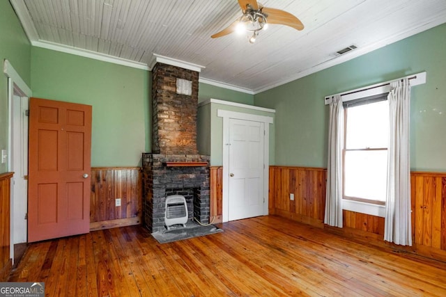 unfurnished living room featuring hardwood / wood-style floors, wooden walls, visible vents, and a wainscoted wall