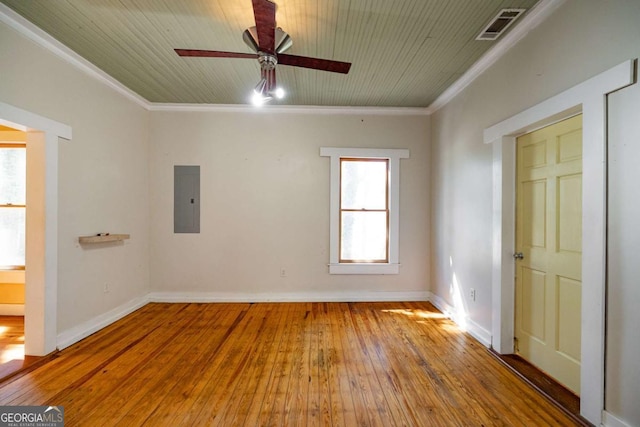 spare room with electric panel, visible vents, crown molding, and hardwood / wood-style flooring