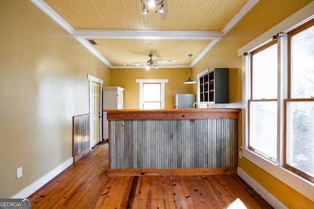 kitchen featuring visible vents, crown molding, baseboards, freestanding refrigerator, and hardwood / wood-style flooring