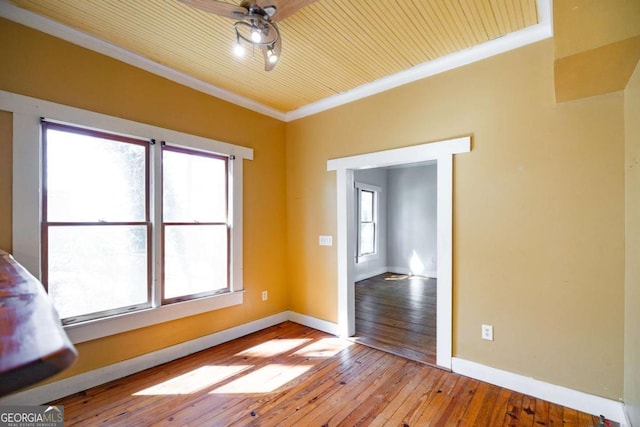 empty room with ceiling fan, hardwood / wood-style floors, baseboards, and ornamental molding