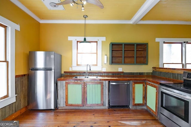 kitchen featuring a sink, crown molding, wood-type flooring, appliances with stainless steel finishes, and dark countertops