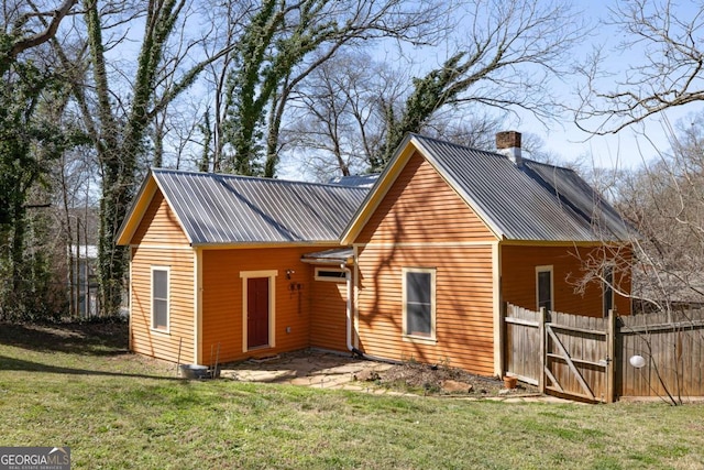 exterior space with a yard, metal roof, and fence