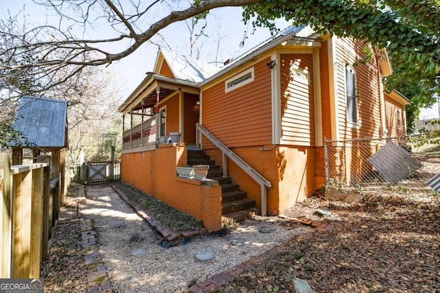 view of home's exterior with stairway, a gate, and fence