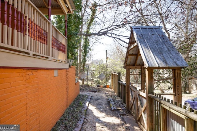 view of side of home featuring brick siding and fence