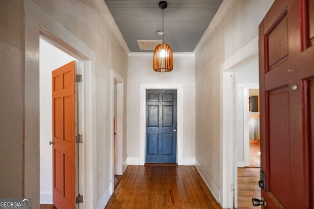 foyer entrance with dark wood-style floors, visible vents, crown molding, and baseboards