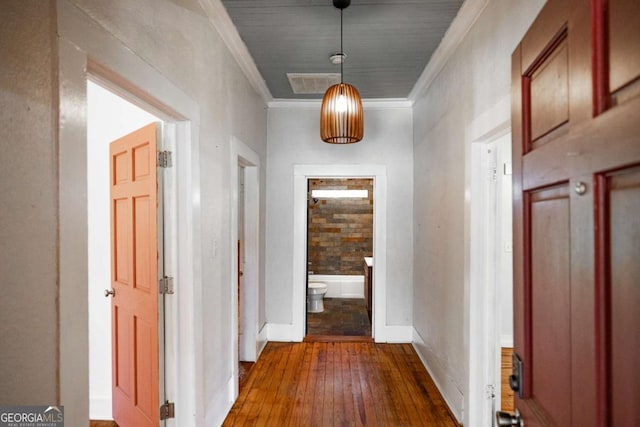 corridor with visible vents, crown molding, baseboards, and hardwood / wood-style floors