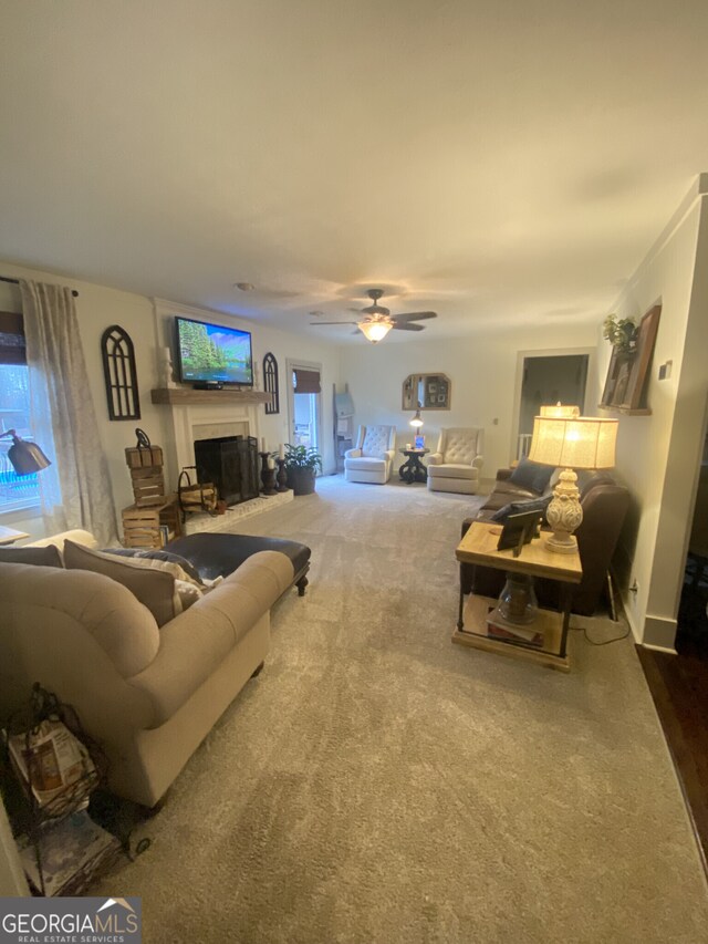 living room featuring a fireplace with raised hearth and dark carpet