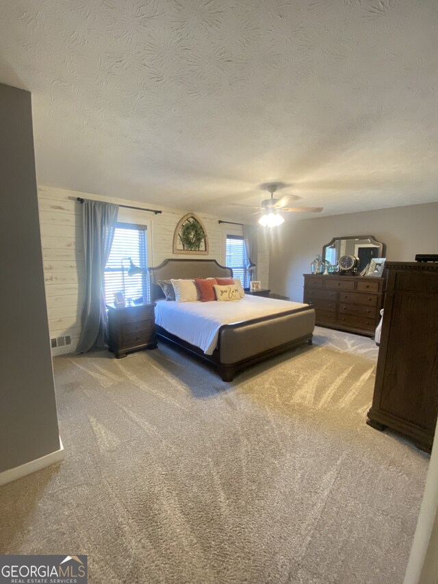 bedroom featuring light colored carpet, a textured ceiling, and a ceiling fan