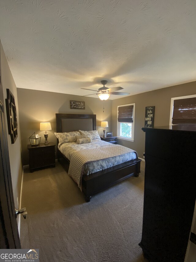 carpeted bedroom featuring a textured ceiling, ceiling fan, and baseboards