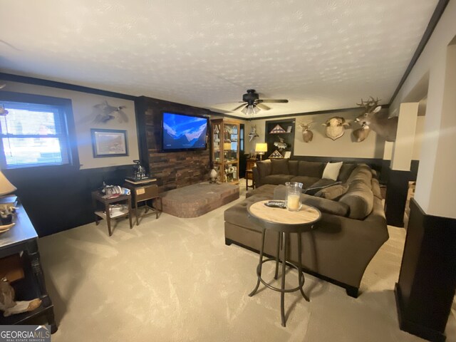 living area featuring carpet, a textured ceiling, and a ceiling fan