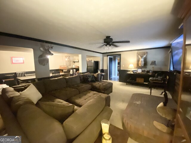 living room featuring a ceiling fan, crown molding, and carpet flooring