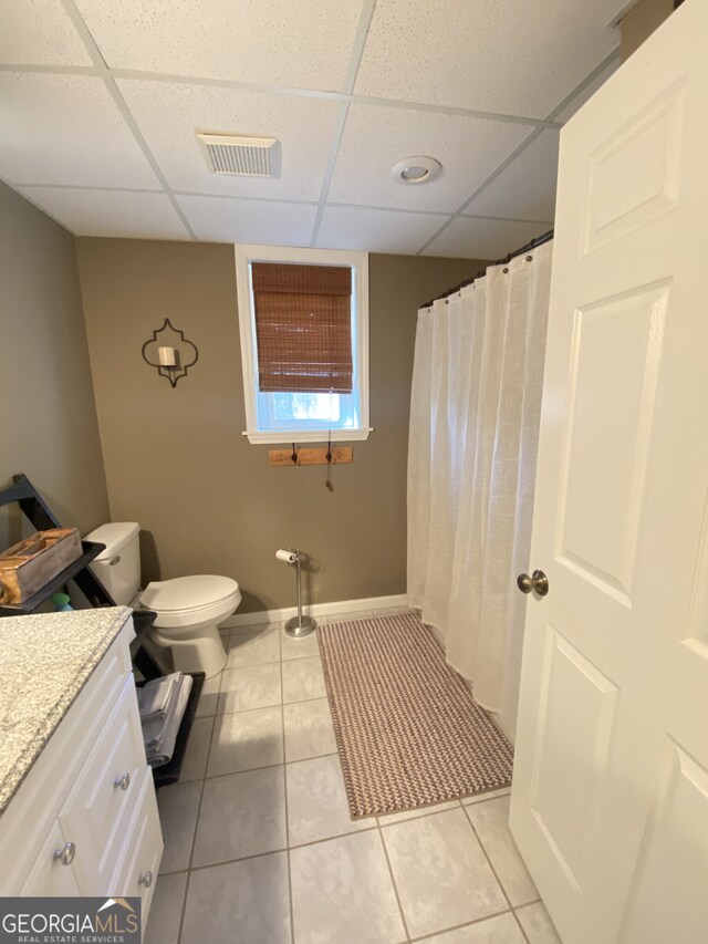 bathroom with a paneled ceiling, vanity, tile patterned flooring, toilet, and baseboards