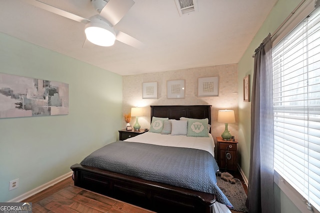 bedroom featuring visible vents, multiple windows, baseboards, and wood finished floors