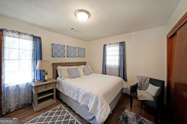 bedroom featuring visible vents, multiple windows, a textured ceiling, and wood finished floors