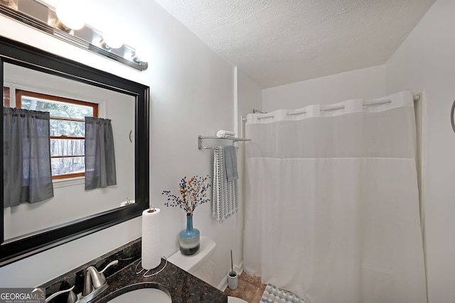 bathroom with curtained shower, a textured ceiling, and vanity