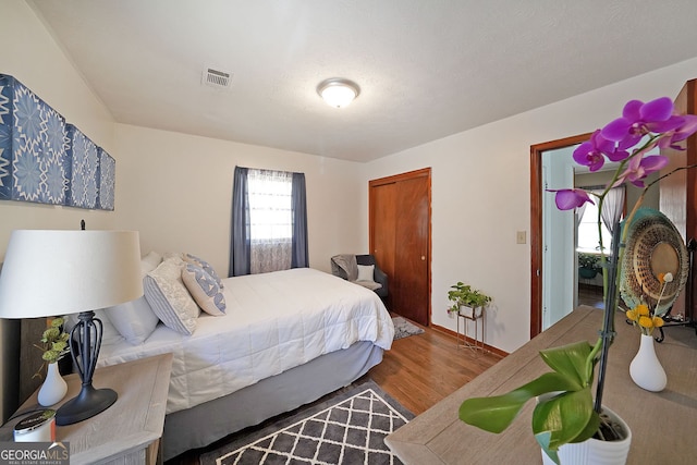 bedroom featuring a closet, visible vents, baseboards, and wood finished floors