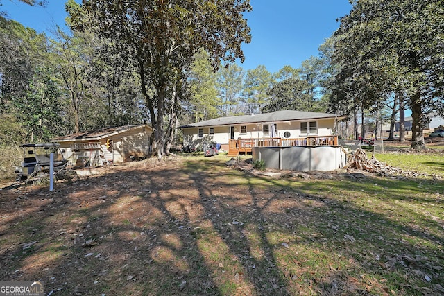 rear view of property with a deck and an outdoor pool