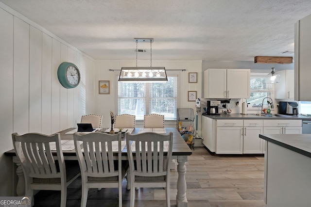 dining space with light wood finished floors, visible vents, and a textured ceiling