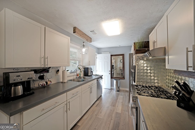 kitchen with visible vents, under cabinet range hood, appliances with stainless steel finishes, white cabinetry, and a sink