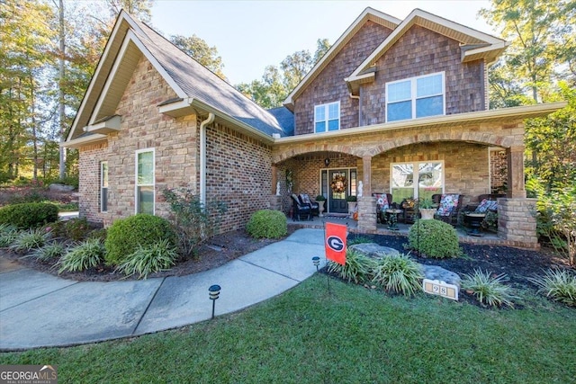 craftsman-style house featuring stone siding, a porch, and a front yard