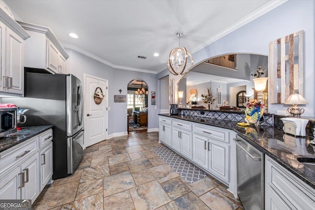 kitchen with arched walkways, appliances with stainless steel finishes, ornamental molding, and stone tile floors